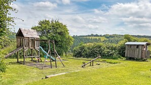 A playground with a slide and swings, a wooden structure, and a small shed in a grassy field. - 3 bedroom accommodation in Dulverton (Dulverton)