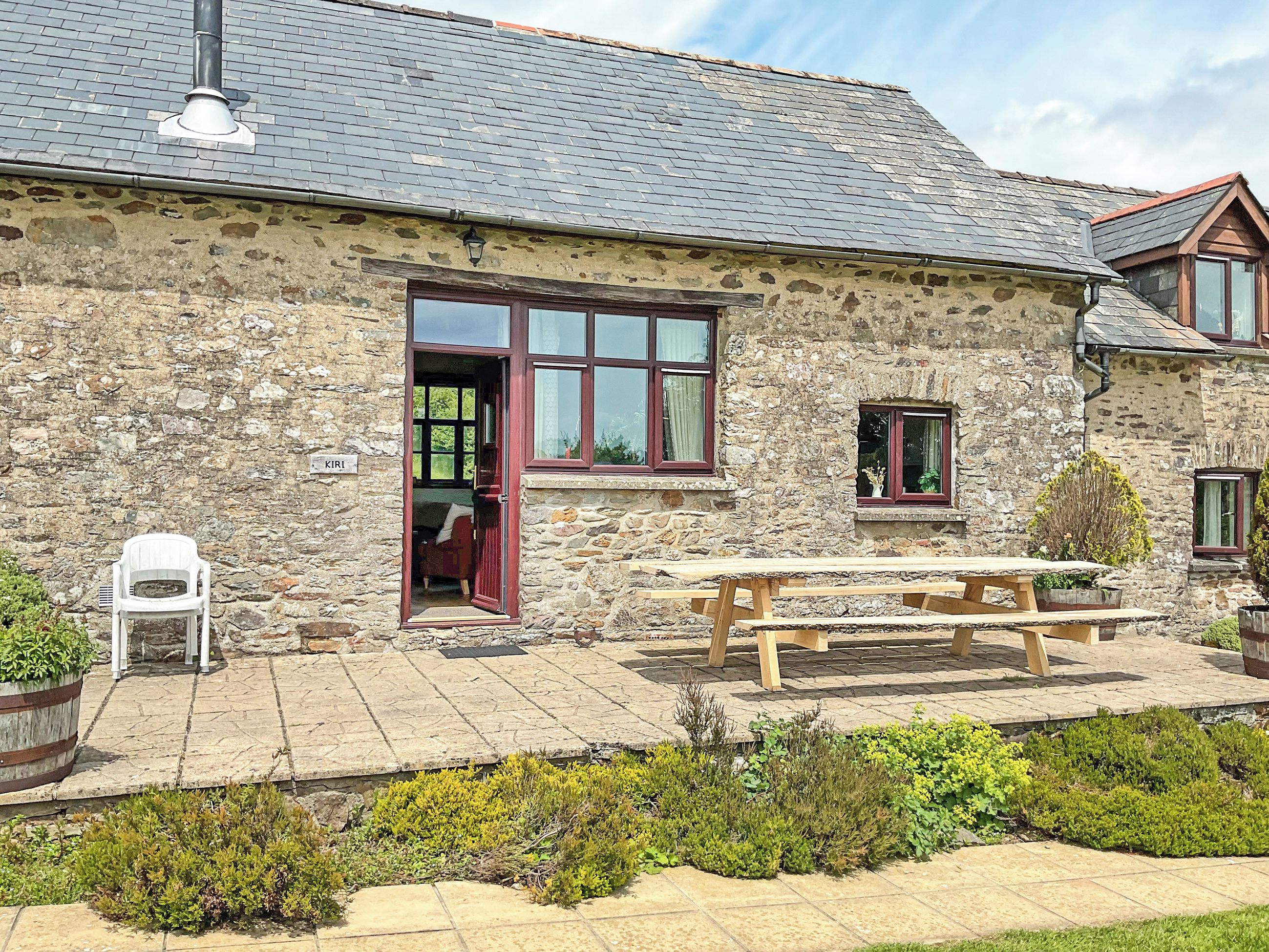 A stone building with a wooden door, a window, and a picnic table.