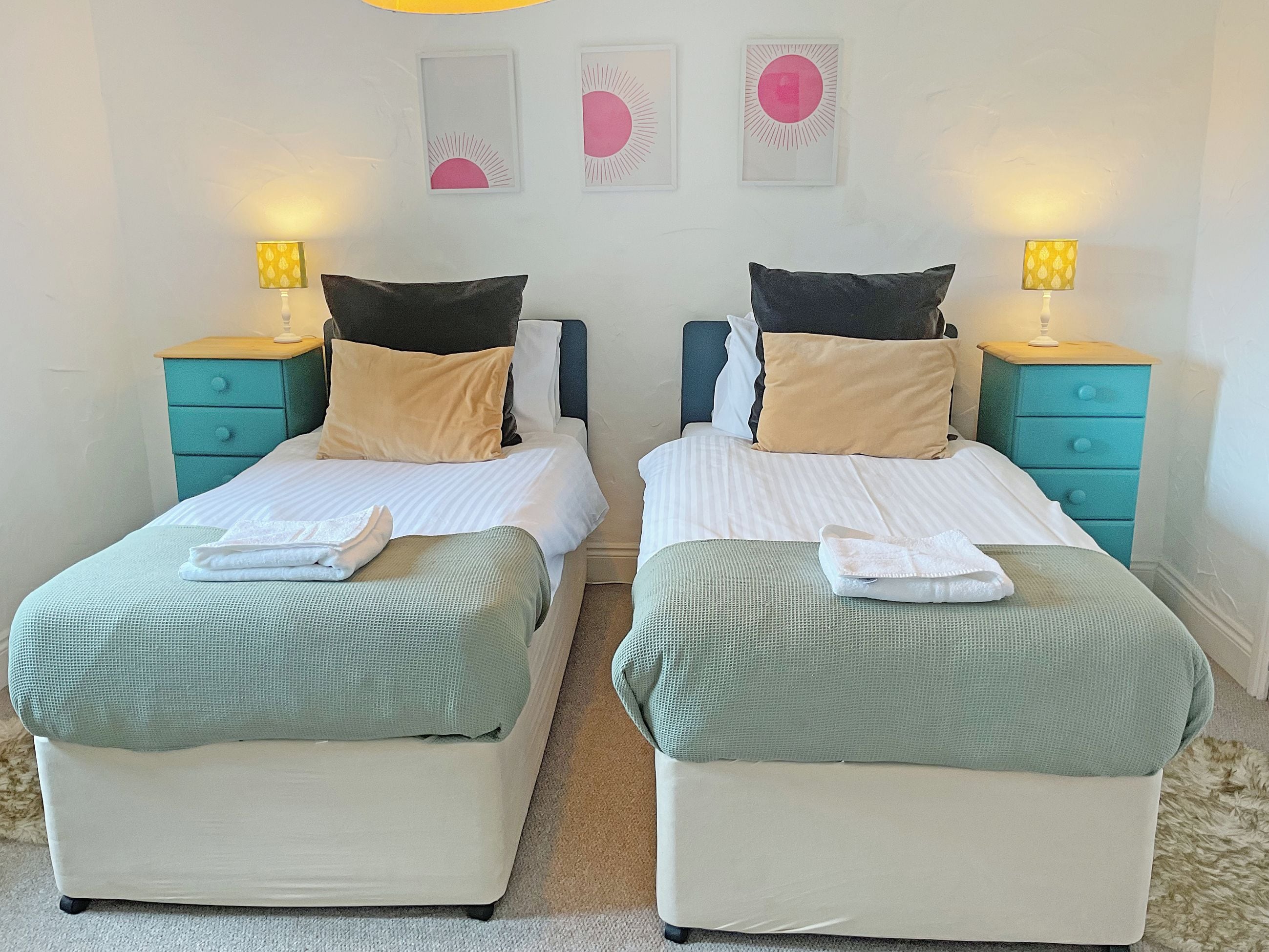 Habitación doble con dos camas, cada una con una almohada, una mesita de noche y una lámpara.