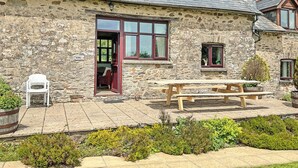 A stone building with a wooden door, a window, and a picnic table. - 3 bedroom accommodation in Dulverton (Dulverton)