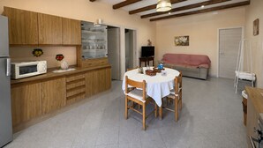 Cocina compacta con armarios de madera, microondas y una mesa de comedor con sillas.