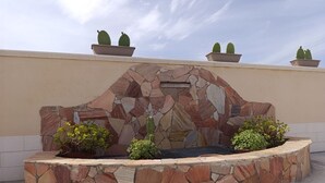 Un muro de piedra con una zona de barbacoa integrada y cactus en macetas.