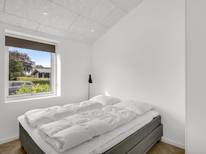 Un dormitorio con cama, ventana y lámpara en el techo.