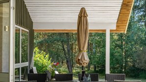 An outdoor patio with wicker furniture, a table, and a covered umbrella. - "Laris" -  from the sea by Interhome (Hadsund)