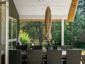 Eine Terrasse im Freien mit Korbmöbeln, einem Tisch und einem Sonnenschirm.