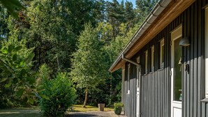 A pathway leading to a building with a dark exterior and a wooden roof. - "Laris" -  from the sea by Interhome (Hadsund)