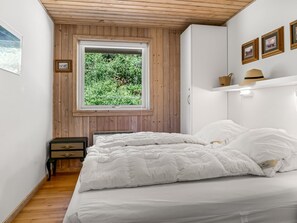 A bedroom with a large window, a bed, a nightstand, and a shelf with decorative items. - "Laris" -  from the sea by Interhome (Hadsund)