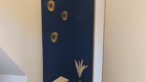 A room with a dark blue accent wall, a wooden stool, a vase with pampas grass, and three wall-mounted circular decorations. - Le Saphir d'Ault—The beach is 100 meters away, and restaurants are just a stone's throw away (Ault)