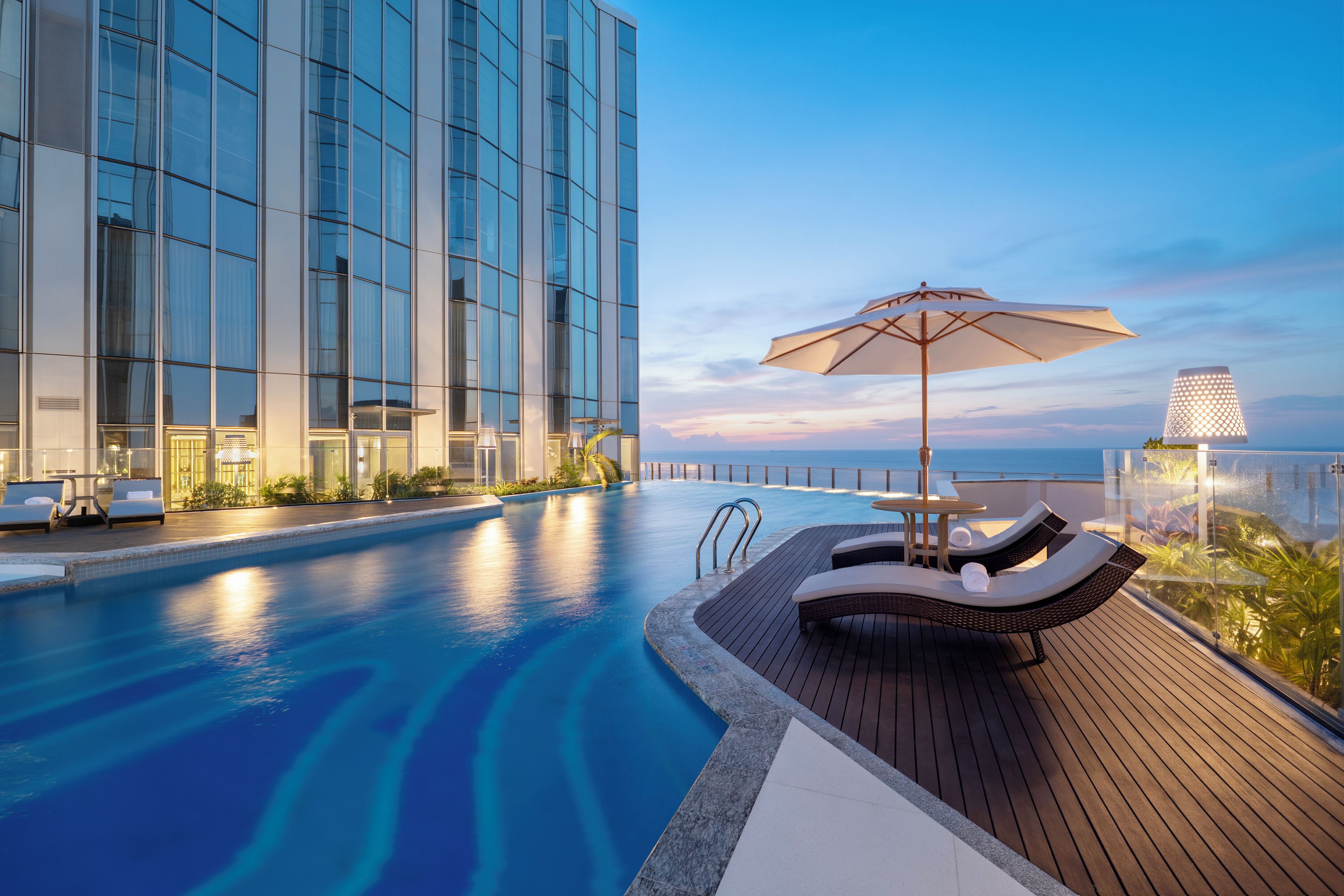 Een modern hotel met een zwembad, ligbedden en uitzicht op de oceaan.
