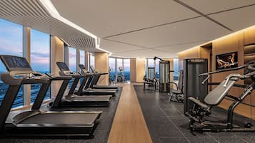A modern gym with treadmills, weight machines, and a view of the city.