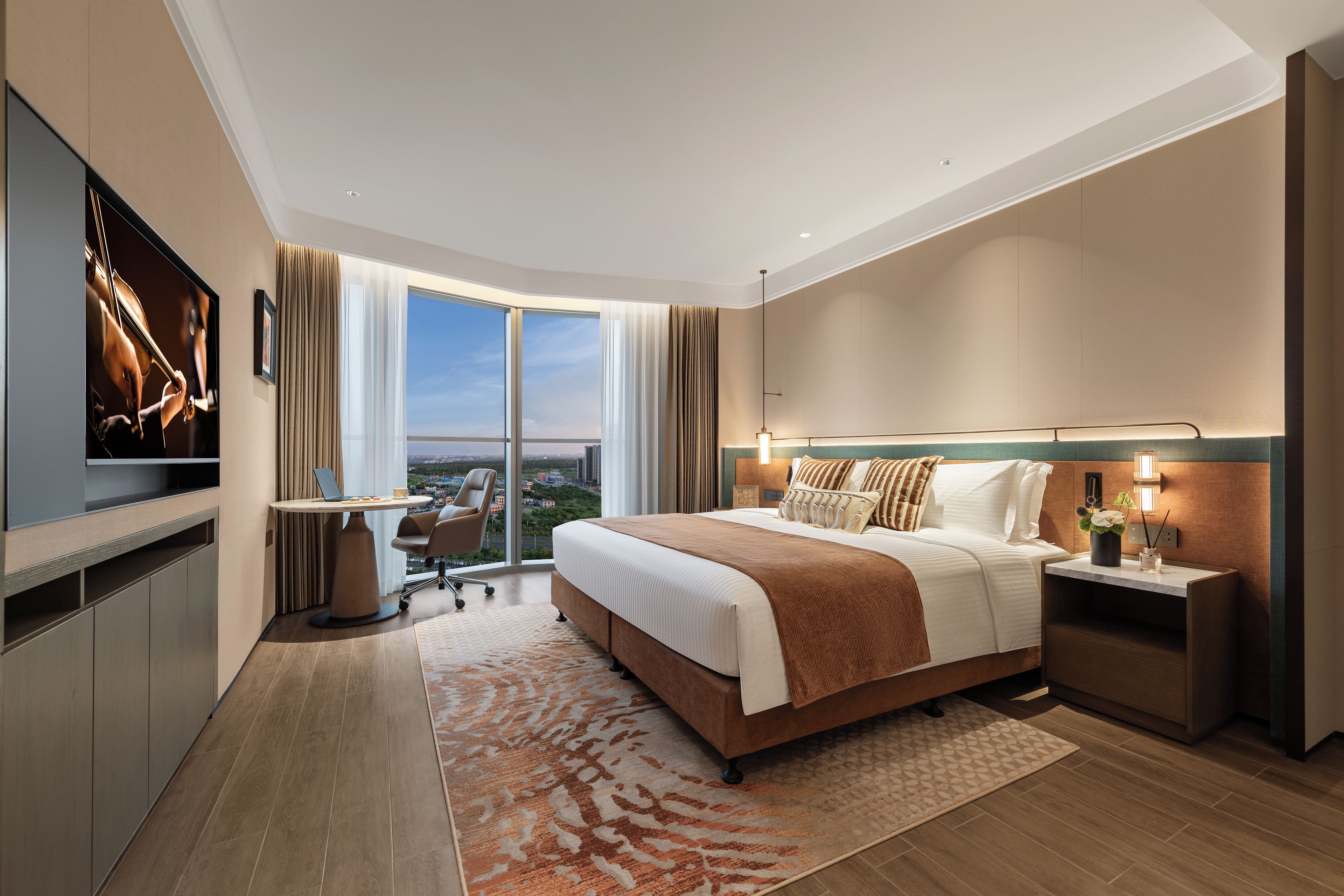Een moderne hotelkamer met een groot bed, een bureau, een televisie en uitzicht op de stad.
