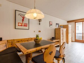 Un coin repas avec une table et des chaises en bois, un luminaire suspendu et un mur orné de tableaux.