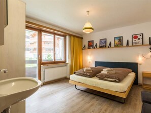 A bedroom with a bed, a bedside table, a window, a radiator, and a wall-mounted shelf with pictures. - Cresta Appartement/Fewo 4-Bettwohnung Nr. 6 by Interhome (Saas-Fee)