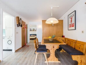 Ein Essbereich mit einem Holztisch, Bänken, einer hängenden Leuchte und einem gerahmten Poster an der Wand.