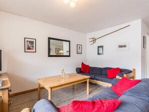 Un salon meublé avec un canapé, une table basse en bois et un miroir au mur.