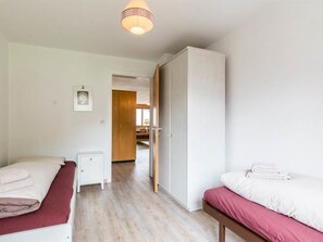 Une chambre d’hôtel avec deux lits, une armoire, une table de chevet et une porte donnant sur une salle de bain.