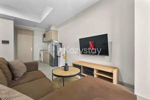 A modern living room with a sofa, a round table, and a TV mounted on the wall. - Taori by Kozystay - Kemayoran (Central Jakarta)