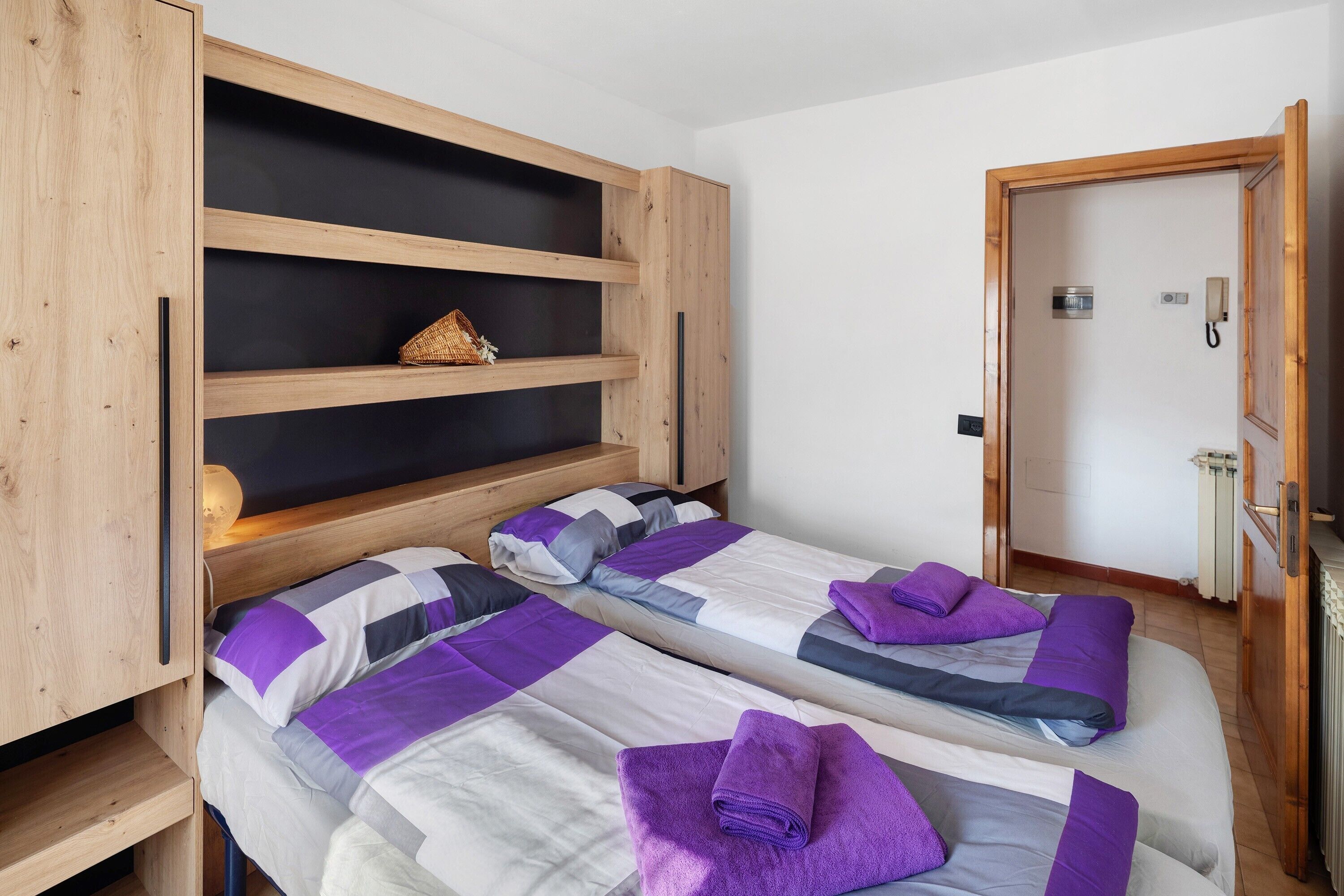 Une chambre avec deux lits, des têtes de lit en bois et une étagère intégrée.