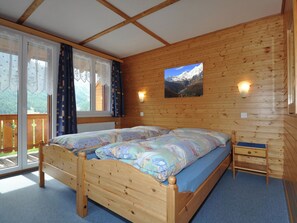 A wooden cabin room with a double bed, a small bedside table, and a window with curtains. - Chalet Ideal Appartement/Fewo 3-Bettwohnung Nr. 4 by Interhome (Saas-Fee)
