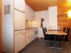 A compact kitchen with white cabinets, a wooden table, and black chairs. - Chalet Ideal Appartement/Fewo 3-Bettwohnung Nr. 4 by Interhome (Saas-Fee)
