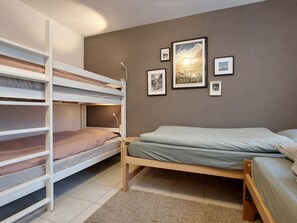 Ein Schlafsaalzimmer mit Etagenbetten, einem Bett und Wandbildern.