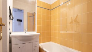 A bathroom with a white sink, a bathtub, and yellow-tiled walls. - Classic Riviera Escape with Pool, Grasse (Grasse)