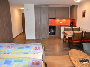 Une chambre d’hôtel comprenant un lit, une table à manger avec des chaises, un coin cuisine et une salle de bain.