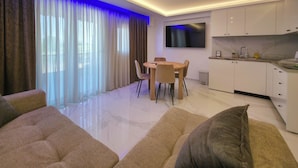 Ein modernes Wohnzimmer mit Essbereich, einer Küche und einem an der Wand befestigten Fernseher.