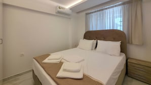 Ein Hotelzimmer mit Bett, Nachttisch, Klimaanlage und einem Fenster mit Vorhängen.