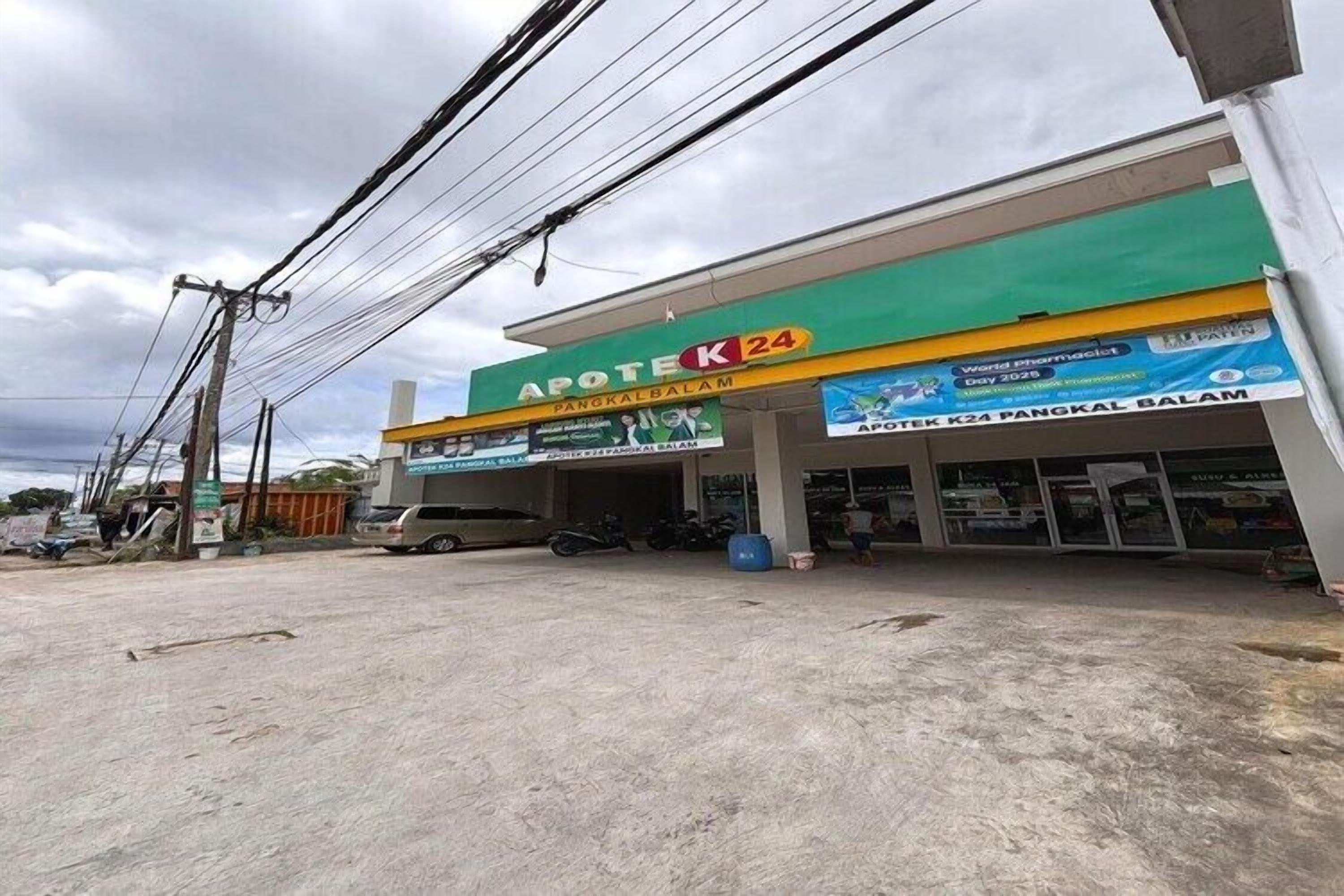 A gas station with a green and yellow sign, multiple fuel pumps, and a parking area.