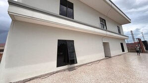 Un edificio de dos pisos con techo plano, ventanas amplias y un balcón visible.