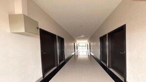 Un pasillo largo y estrecho con puertas a ambos lados, que da acceso a habitaciones individuales.