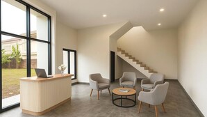 Zona de recepción con mostrador, dos sillones, una mesita redonda y una escalera.