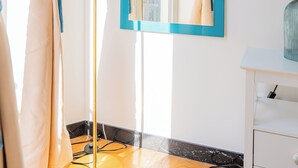 Una habitación con un espejo grande, un adorno de plumas azules y un armario blanco.