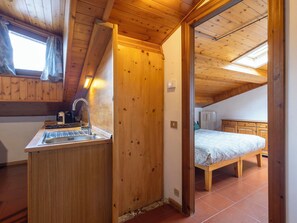 Un intérieur en bois comprenant un coin cuisine, un lit et une vue sur l’extérieur.
