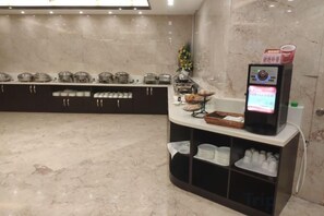 Zona de bufé hotelero con un mostrador de autoservicio y una variedad de alimentos.