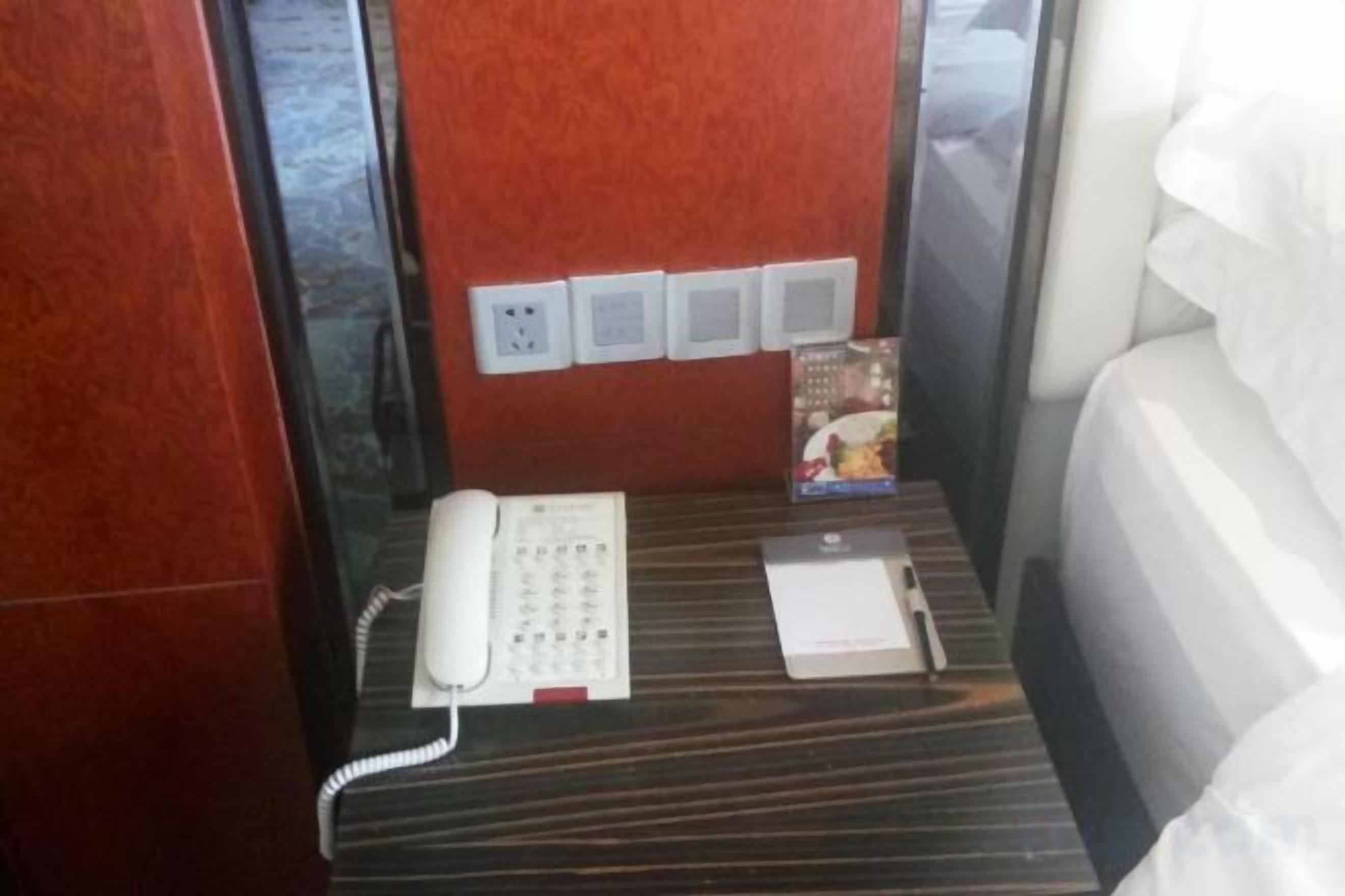 Una habitación de hotel con teléfono, mesita de noche y cama.