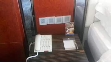 Una habitación de hotel con teléfono, mesita de noche y cama.