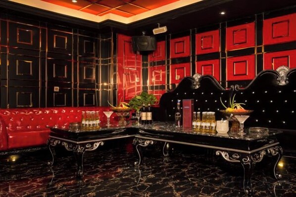 Un espace bar avec un canapé rouge, un comptoir de bar en marbre noir et un éclairage décoratif.