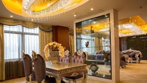 A luxurious dining room with a chandelier, ornate table, and purple upholstered chairs.