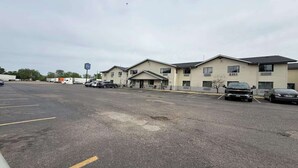 A parking lot with several cars and a building with multiple windows and a flat roof.