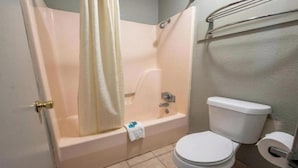 A bathroom with a bathtub, toilet, and a shower curtain. - King Bed | Smoking | Forrest City (Forest City, AR)