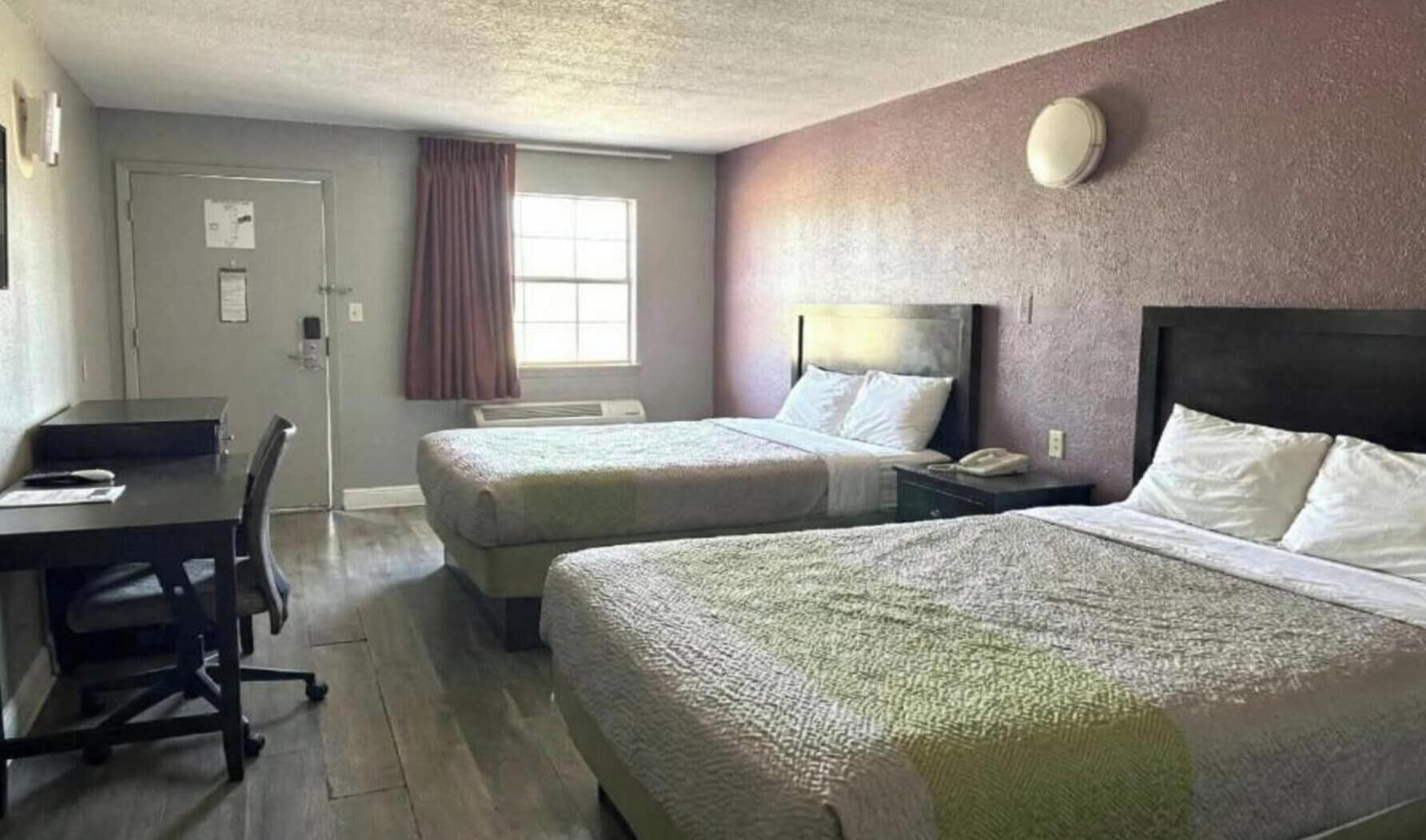 A hotel room with two beds, a desk, and a chair.