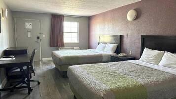 Hotellihuone, jossa on kaksi sänkyä, työpöytä ja tuoli.
