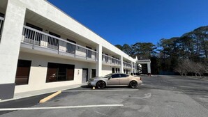 A multi-story building with a parking lot and a car parked in front.