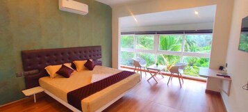 Un dormitorio con una cama grande, un escritorio y una ventana con vistas a zonas verdes.