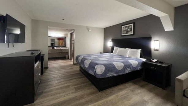 A bedroom with a bed, bedside table, and a TV mounted on the wall.