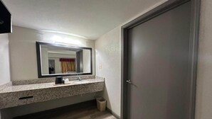 A bathroom with a granite countertop, a sink, a mirror, and a door.
