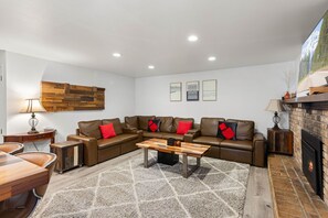 A modern living room with a sectional sofa, a wooden coffee table, a fireplace, and a mounted artwork. - Tahoe Lake & Mountain Retreat (Carnelian Bay)