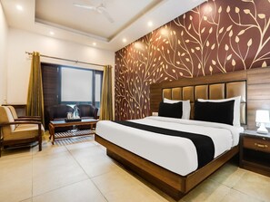 Ein Hotelzimmer mit einem großen Bett, einem Schreibtisch, einem Stuhl, einem Fenster und einer Wandverzierung.